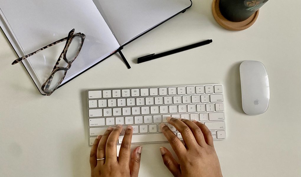 desk scene of hands typing at a keyboard